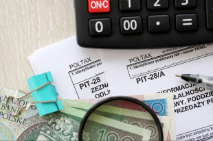 banknoty, kalkulator i długopis na tle różnych formularzy PIT